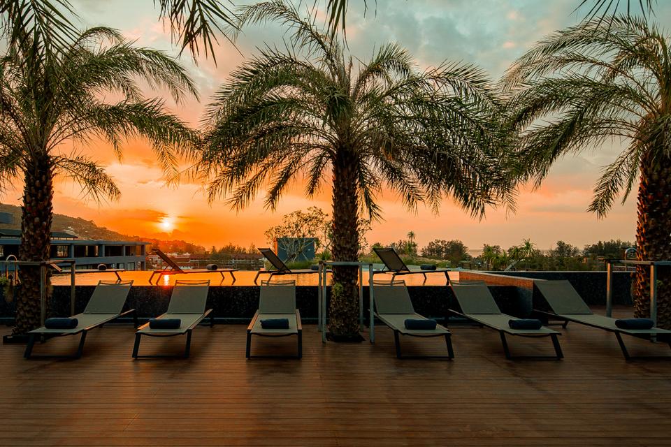 Sunset over palms from the rooftop infinity pool at CityGate Kamala